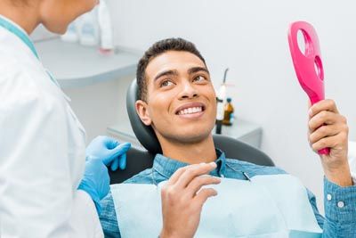 patient smiling in the mirror after dental implants helped restore his smile