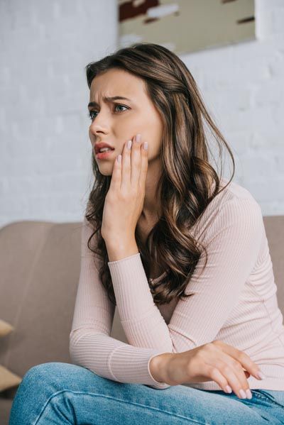 woman holding her mouth due to tooth pain